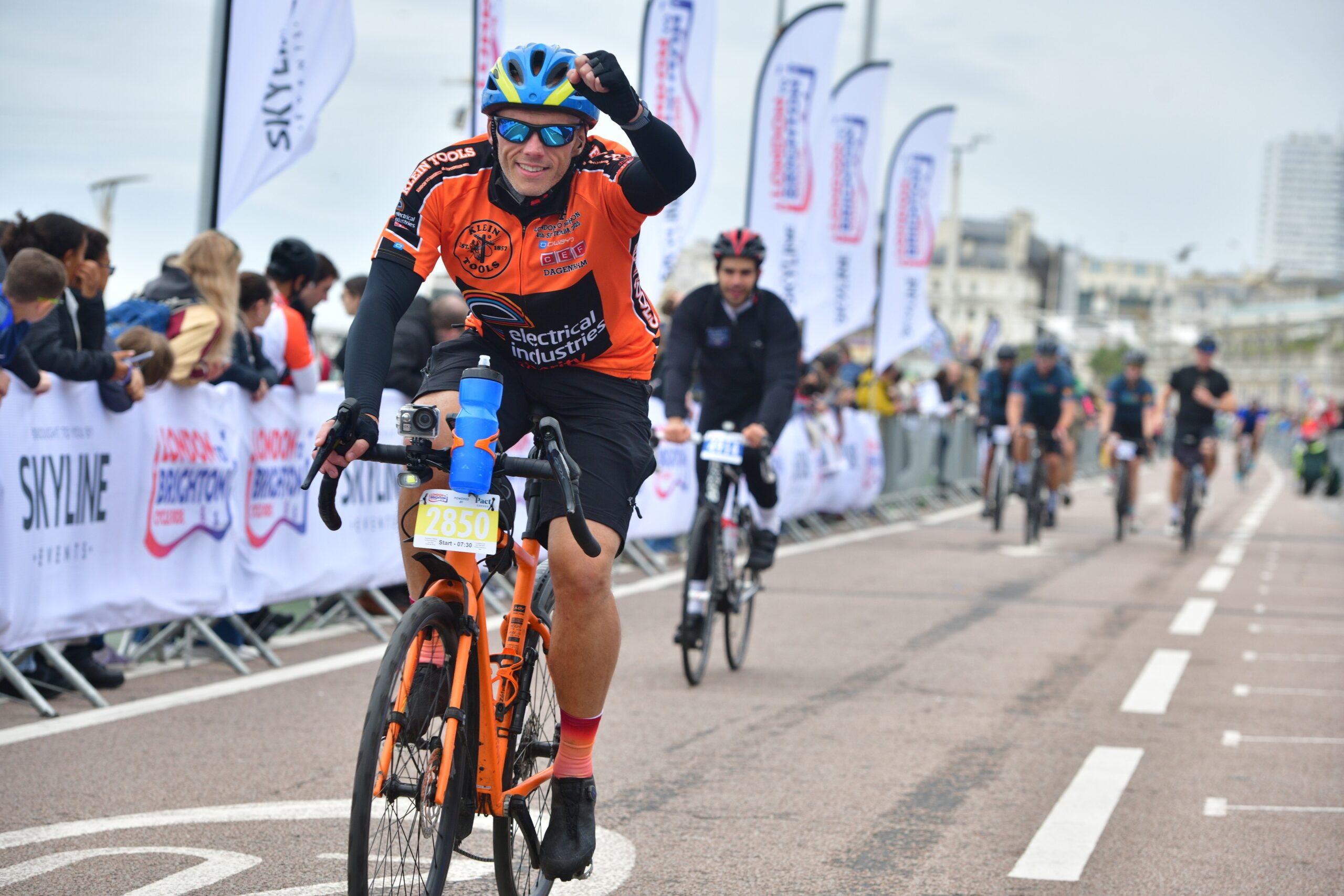 Terry raises his hand in a triumphant fist while cycling towards the finish line in Brighton