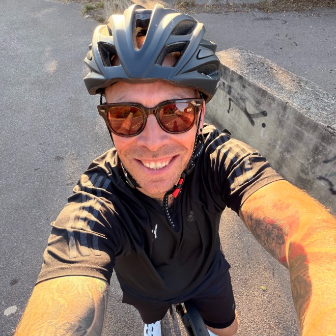 Dan Frosts smiles in a selfie whilst wearing a helmit and sitting on his bike